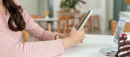 Woman use smartphone to scan QR code to pay in cafe restaurant with a digital payment without cash. Choose menu and order accumulate discount. E wallet, technology, pay online, bank app. photo