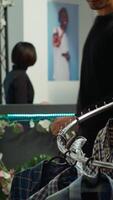 Vertical Male shopper examines an array of stylish apparel in a well organized retail space, searching for items to represent his personal style. Fashion display of trendy quality garments. Camera A. video