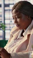 Vertical Female CEO discussing business ideas with her team on social media, receiving project updates form employees via text messages. Black goal oriented entrepreneur with determination. Camera A. video