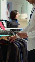 Vertical Middle eastern clothing store employee verifying merchandise stock on device, preparing the new collection on display for customers. Ensuring a great luxurious shopping experience. Camera A. video