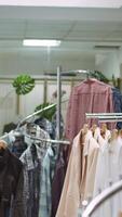 Vertical Designer boutique assistant arranging a vibrant selection of garments on racks, highlighting stylish new collection apparel and creating a welcoming shopping experience for customers. Camera B. video