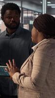 Vertical African american executive staff are engaged in administrative tasks, reviewing analytics reports and corporate data to ensure alignment with company objectives for effective management. Camera A. video