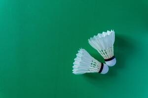 Two shuttlecocks against a green surface, copy space photo