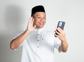 Asian man calling with happy and excited expression. Man using conferencing meeting online app at home. photo