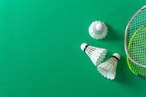Flat lay of badminton rackets and shuttlecocks on a vibrant green surface. photo