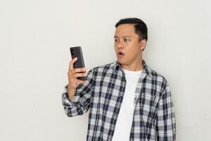 Asian man pointing to mobile phone with afraid and surprised expression. Promotion cocept photo