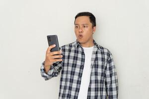 Asian man pointing to mobile phone with afraid and surprised expression. hearing bad news concept photo