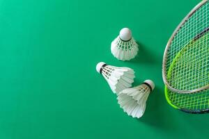 Badminton sport concept. Two badminton rackets and a shuttlecock over green background. photo