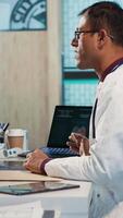 Vertical Indian general practitioner and patient engage in a medical consultation with diagnostic tools and x ray text results for scan interpretation. Showcasing healthcare practices and research. Camera A. video