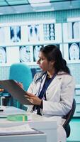 Vertical Healthcare provider consulting male patient and reviewing x ray test results, utilizing technology for accurate analysis and patient care management in a medical environment. Camera B. video