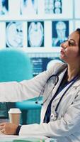 Vertical Physician meeting with patient to discuss medical test results in a cabinet, using advanced diagnostic tools to interpret x ray scans, demonstrating a professional healthcare approach. Camera A. video