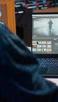 Vertical editor trimming segments of drone shot footage, working on promotional clip in home office. Videographer splicing film pieces, editing them using professional software on laptop, camera A video