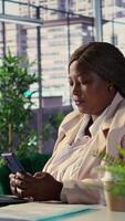 Vertical African american CEO texting messages about updates or business ideas with her team, shares project insight online on internet connection. Successful goal oriented director. Camera B. video