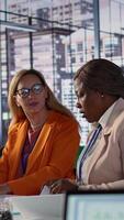 Vertical Ambitious women executives collaborating in a diverse work environment, discussing strategies for corporate growth and evaluating budget numbers. Road to a success story. Camera B. video