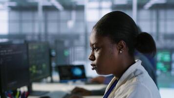 Close up of programmer in data center implementing AI predictive maintenance systems. Focus on IT professional in server hub using artificial intelligence to identify hardware failures, camera A video
