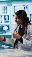 Vertical Indian general practitioner and patient engage in a medical consultation with diagnostic tools and x ray text results for scan interpretation. Showcasing healthcare practices and research. Camera B. video