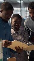 Vertical Female employee and manager gathered around a workstation discussing objectives and strategizing solutions to solve administrative tasks faster. Aligning business goals and milestones. Camera A. video