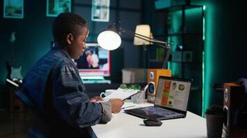 Entrepreneur working from home, using laptop, writing notes on paper. Remote worker in personal apartment office transcribing important info on notepad, looking at statistic charts, camera B video