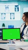 Vertical Indian physician consulting male patient in medical facility next to chroma key, using technology for scan interpretation and diagnostics. Medic giving professional advice based on records. Camera A. video