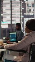 Vertical Black manager wheelchair user reviewing the financial data for the monthly reports, ensuring an accurate revenue balance. Woman with disability solving business operations. Camera B. video