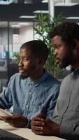 Vertical Business manager sits with a worker to review financial forecasts on pc, leading an analytics evaluation on project development. Achieving organizational goals for growth. Camera B. video