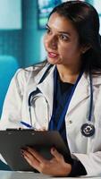 Vertical General practitioner consulting patient and reviewing x ray test results, utilizing technology for analysis and care management in a medical environment. Healthcare provider. Camera A. video