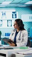 Vertical General practitioner consulting patient and reviewing x ray test results, utilizing technology for analysis and care management in a medical environment. Healthcare provider. Camera B. video