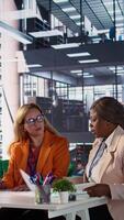 Vertical Diverse business experts sharing ideas for corporate growth planning, analyzing infographics for monthly report task. Powerful women working together to ensure organizational productivity. Camera B. video