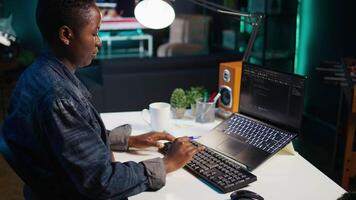 Teleworker in living room office using laptop to do coding for software developing, handheld camera shot. Remote employee typing on device keyboard, solving tasks in apartment, camera B close up video