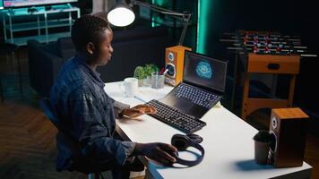 Programmer in living room office typing on keyboard, updating artificial intelligence neural networks, writing binary code scripts. Freelancing system administrator upgrading high tech AI, camera B video