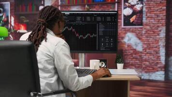 Day trader using PC to purchase and sell stocks, browsing through documentation files to learn how to maximize profits. Investor looking at stock exchange graphs on computer monitor, camera B video