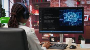 Software developer wearing headphones using computer at home for artificial intelligence computing simulating human brain. IT expert listening music and working with AI deep neural networks, camera B video