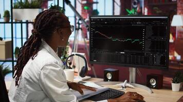 Excited day trader gaining money by selling stocks after browsing through documents to learn how to maximize profits. Thrilled investor celebrating financial gains earned from stock exchange, camera A video