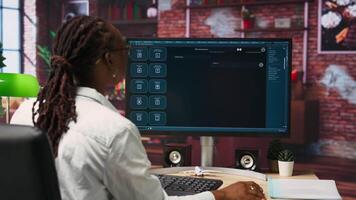 Woman seated at desk using AI LLM chatbot software in modern urban home office. Person requesting help from large language model program on computer in bright apartment workspace, camera B video