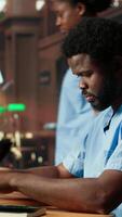 Vertical Medical assistant student reading under a green lamp in the library, doing research about medical methods and preparing for exams. Young man shows his commitment for his career. Camera B. video