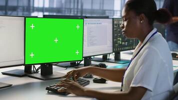 Data center technician using mockup PC, maintaining company network infrastructure. Server hub worker ensuring optimal system performance with green screen computer, camera A video