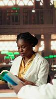 Vertical Young medical students comparing knowledge and class notes at the library, studying together to obtain their residency. Pupils learning healthcare methods by reading surgery notes. Camera B. video