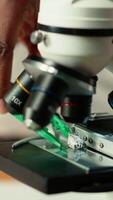 Vertical University student prepares for exam by researching cells and microorganisms under the microscope. Using books and papers from the academic database in the college library. Close up. Camera B. video