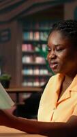 Vertical African american stressed scholar failing to comprehend and memorize lesson notes, struggling to learn the theory for her exam. Frustrated concerned university student at the library. Camera B. video