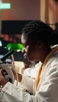 Vertical African american future researcher prepares for exam in a quiet study space, examining biological cells on a microscope. Woman student takes personal notes, career in medical science. Camera A. video