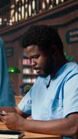Vertical Medical assistant student reading under a green lamp in the library, doing research about medical methods and preparing for exams. Young man shows his commitment for his career. Camera A. video