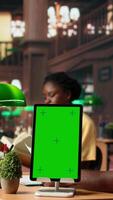 Vertical African american team studying for exams next to chroma key display, reading important information from copy books. Young university students use learning tools from database. Camera A. video