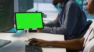 Team of programmer using green screen tablet, working in server farm to optimize it for data processing requirements. Teamworking colleagues coding on chroma key device in data center, camera A video