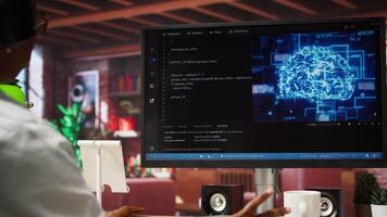 IT engineer drinking coffee, using computer at home for artificial intelligence computing. Close up of remote worker working with AI deep neural networks on desktop PC, camera A video