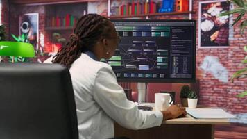 Teleworking computer scientist at home using PC to develop artificial intelligence self learning algorithms. African american woman working with AI machine learning software on PC, camera B video