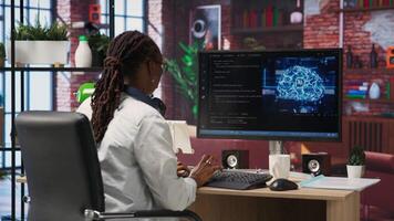 Admin uses computer for artificial intelligence computing simulation, waiting for code to finish compiling. African american woman works with AI deep neural networks at home, camera B video
