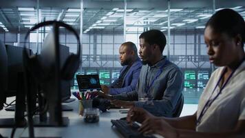 African american data center technicians implement AI predictive maintenance systems. Woman in server hub using artificial intelligence to identify hardware failures, camera A video