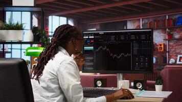 Day trader using PC to purchase and sell stocks, browsing through documentation files to learn how to maximize profits. Investor looking at stock exchange graphs on computer monitor, camera A video