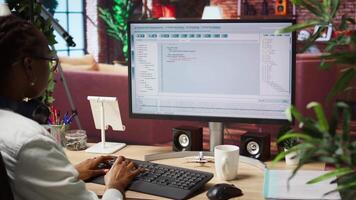 Woman in home office looking at UI on PC screen, typing and executing programming code. Coding application UI used by IT developer writing and testing code in modern apartment, camera A video