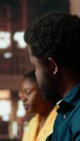 Vertical Black college students comparing their class notes at the university library, scholars team studying and consulting information from copy books. Pupils preparing for their upcoming exams. Camera B. video